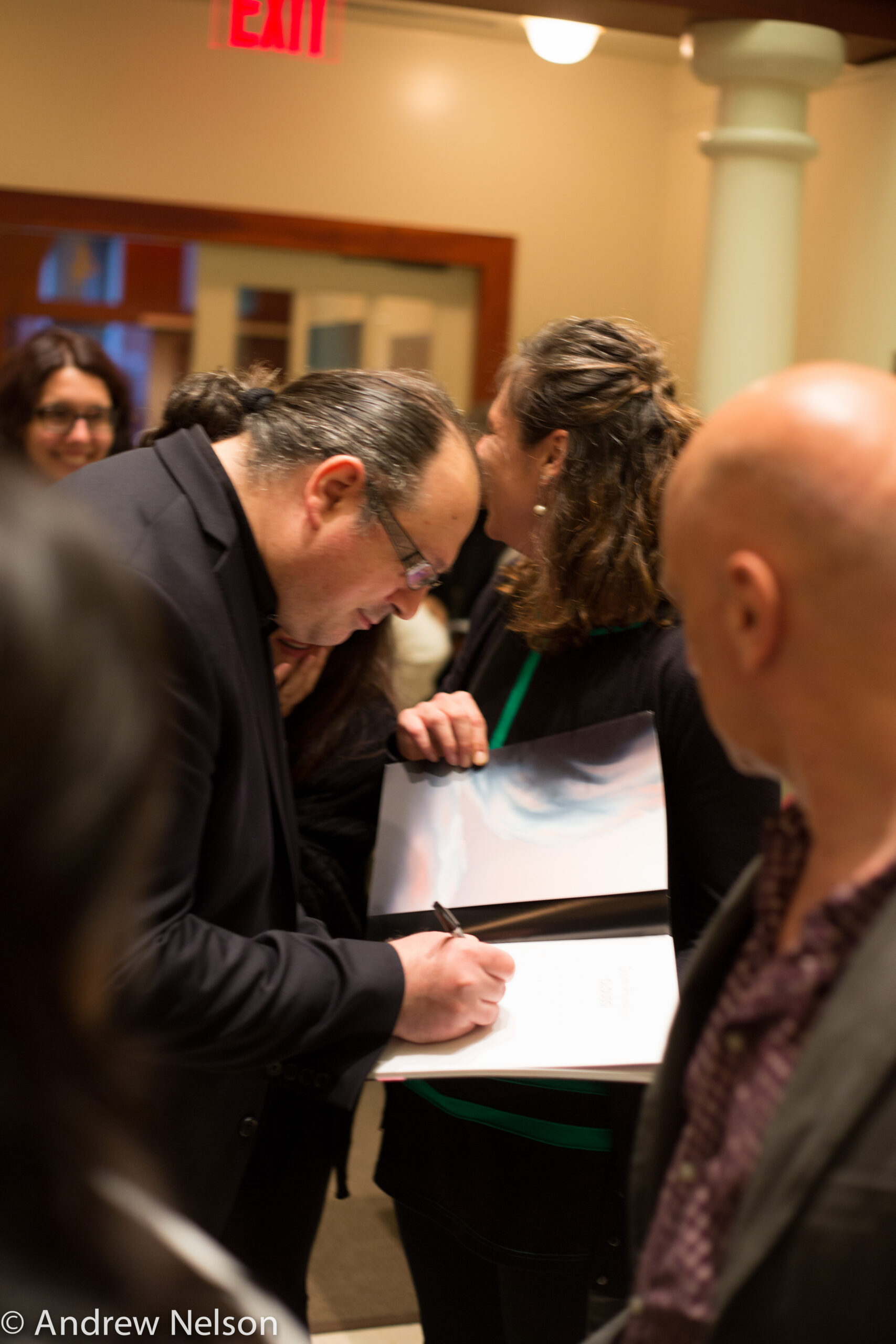 man-signing-on-a-book-from-exhibition-opening-geppy-pisanelli-at-casa-italiana