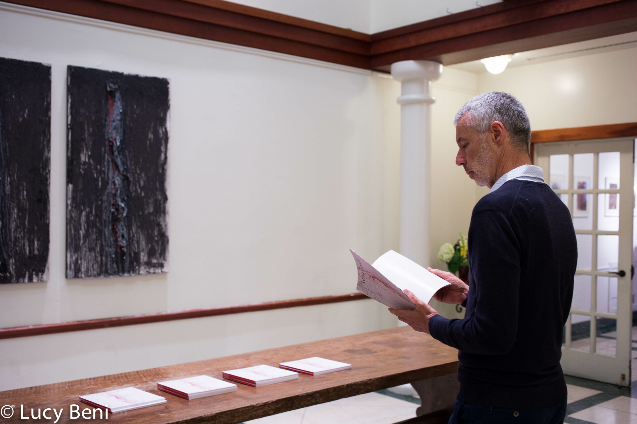 man-reading-book-from-exhibition-opening-luisa-gardini-at-casa-italiana