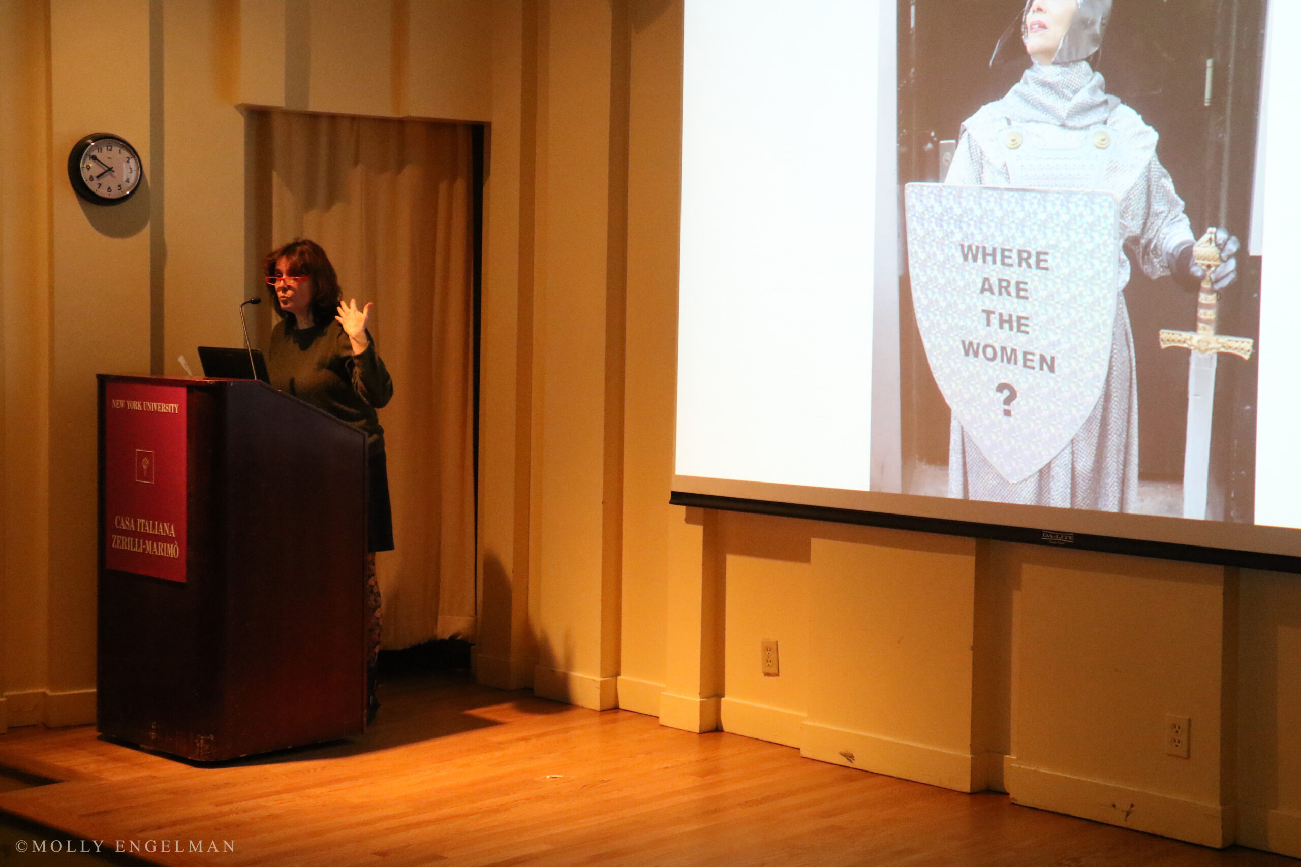 speaker-talking-and-image-being-displayed-on-projector-screen-from-the-triangle-fire-memorial-screening-and-panel-at-casa-italiana