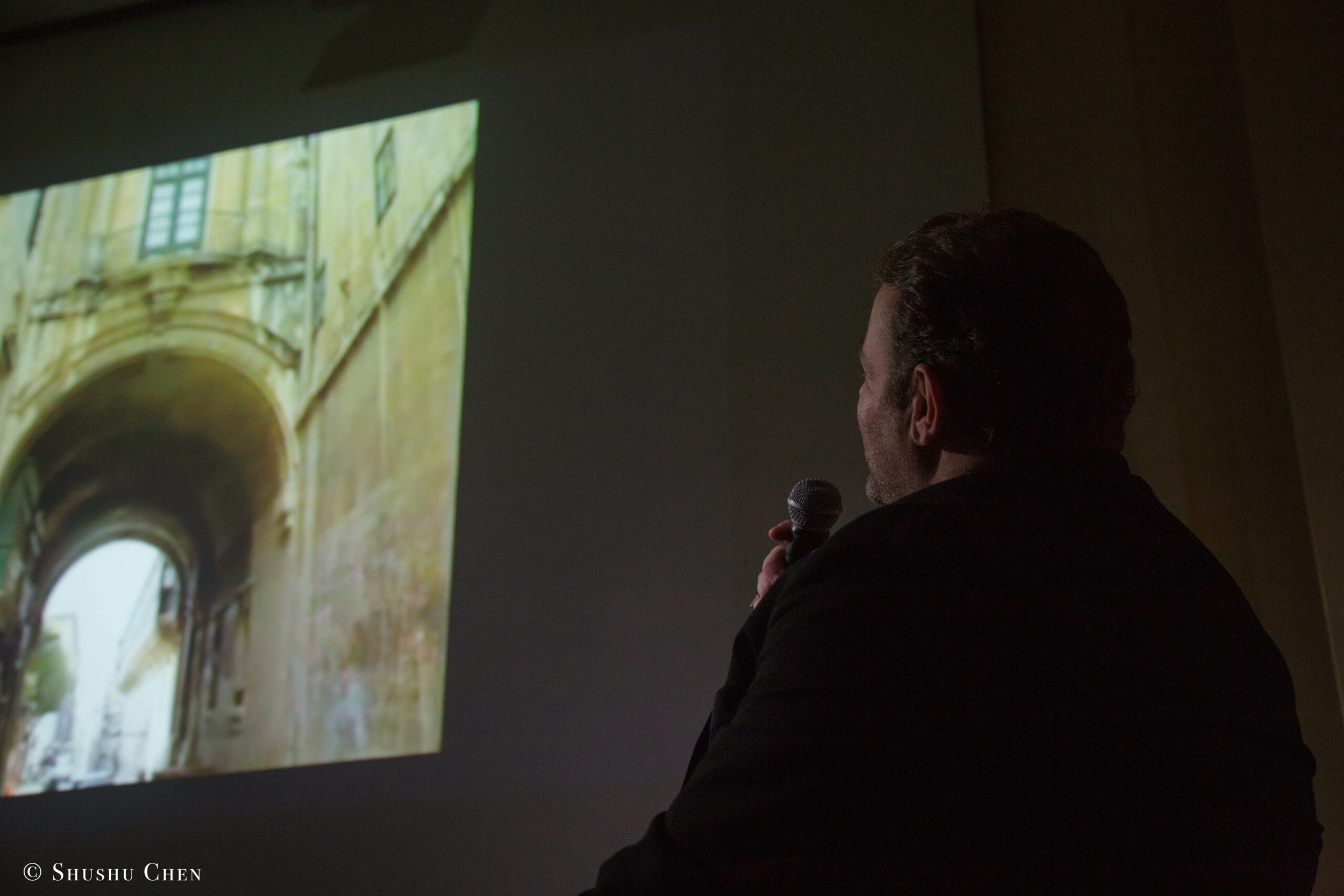 speaker-talking-and-image-being-displayed-on-projector-screen-from-adventures-in-italian-opera-joseph-calleja-at-casa-italiana