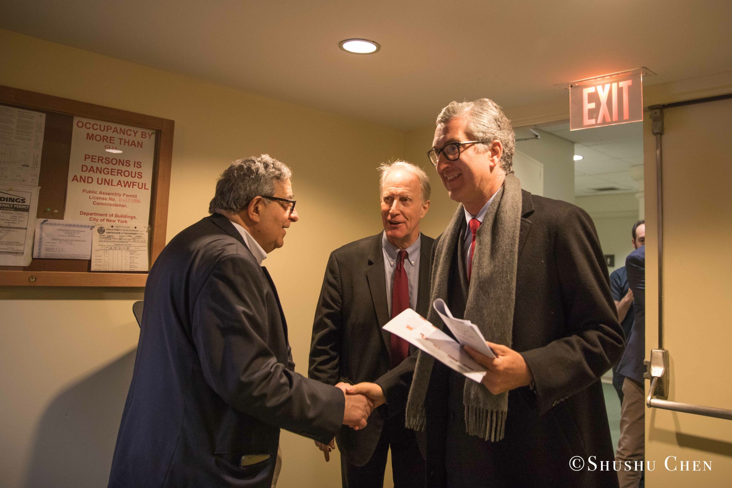three-men-engaging-in-a-friendly-handshake-and-conversation-in-a-hallway-from-Italian-table-talks-at-casa-italiana