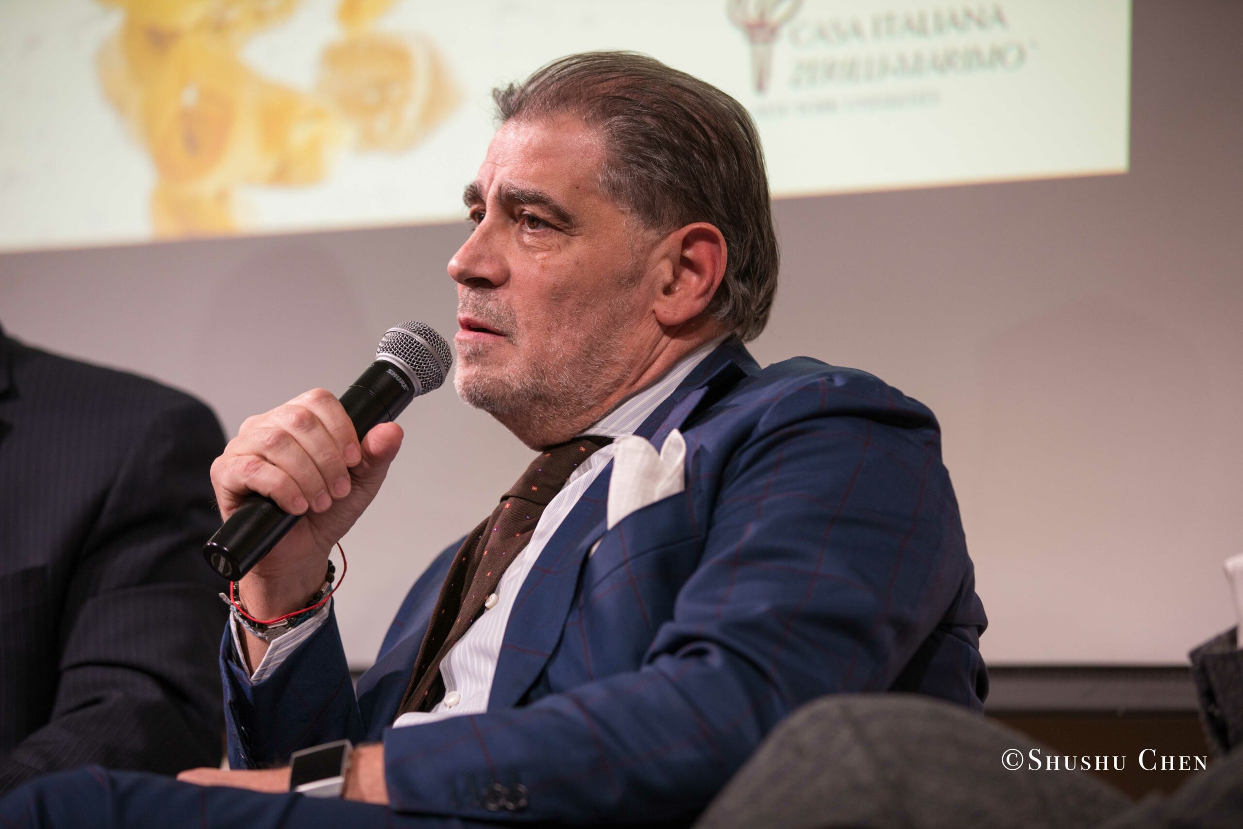 a-middle-aged-man-in-a-blue-suit-speaking-from-Italian-table-talks-at-casa-italiana
