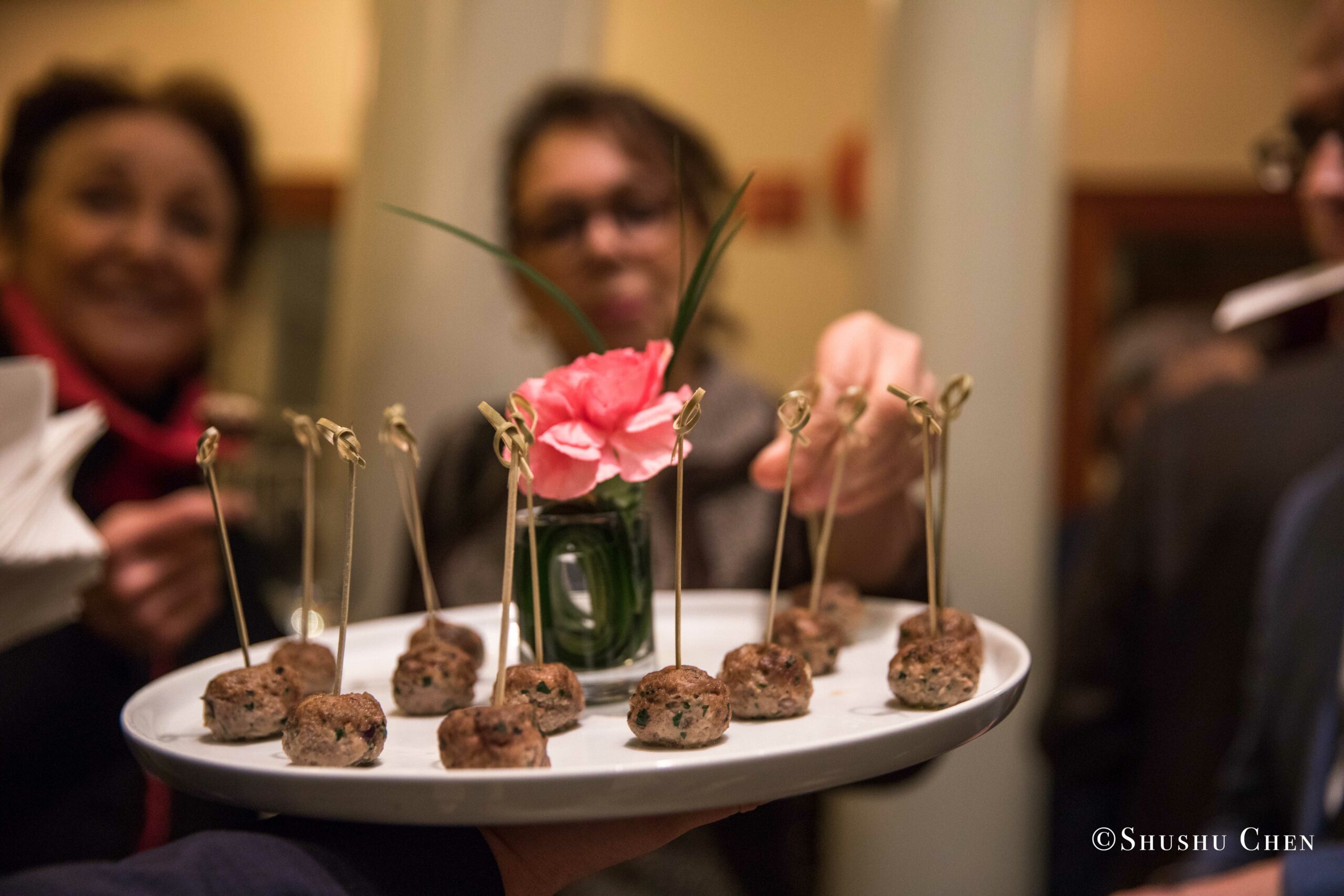 a-server-holds-a-tray-of-appetizers-garnished-with-a-pink-flower-from-Italian-table-talks-at-casa-italiana
