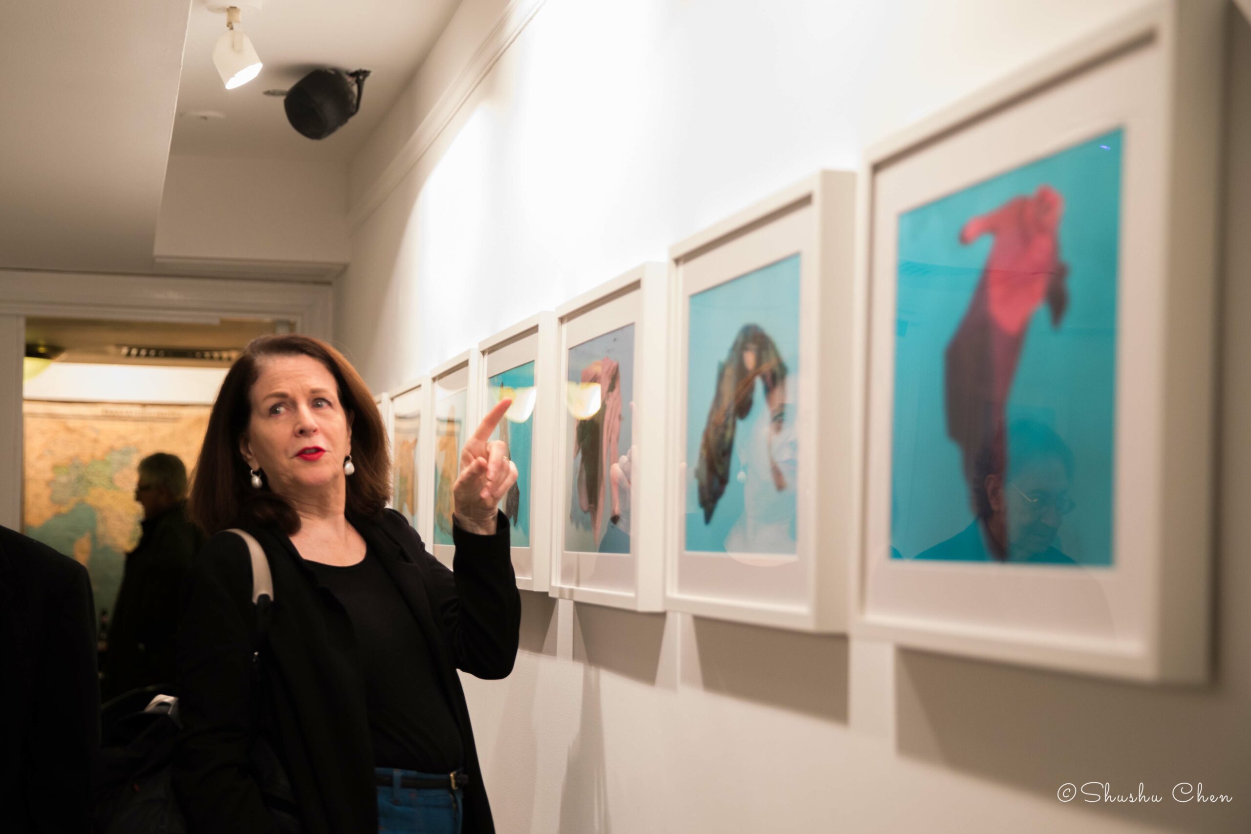woman-pointing-at-artworks-on-wall-from-exhibition-migration-at-casa-italiana