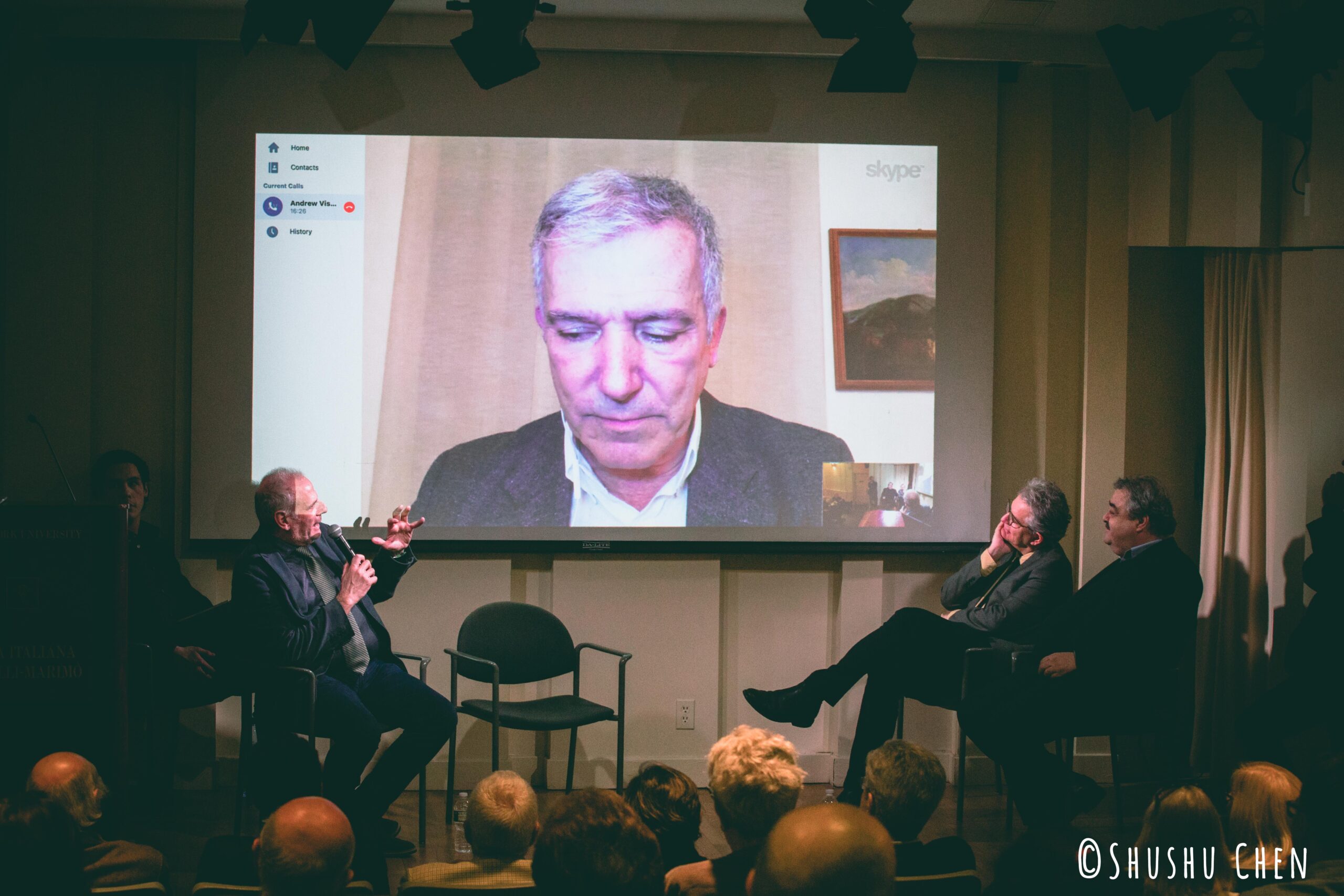 stefano-talking-and-speaker-looking-at-the-projector-screen-from-panel-discussion-giornali-locali-in-un-mondo-globale-at-casa-italiana