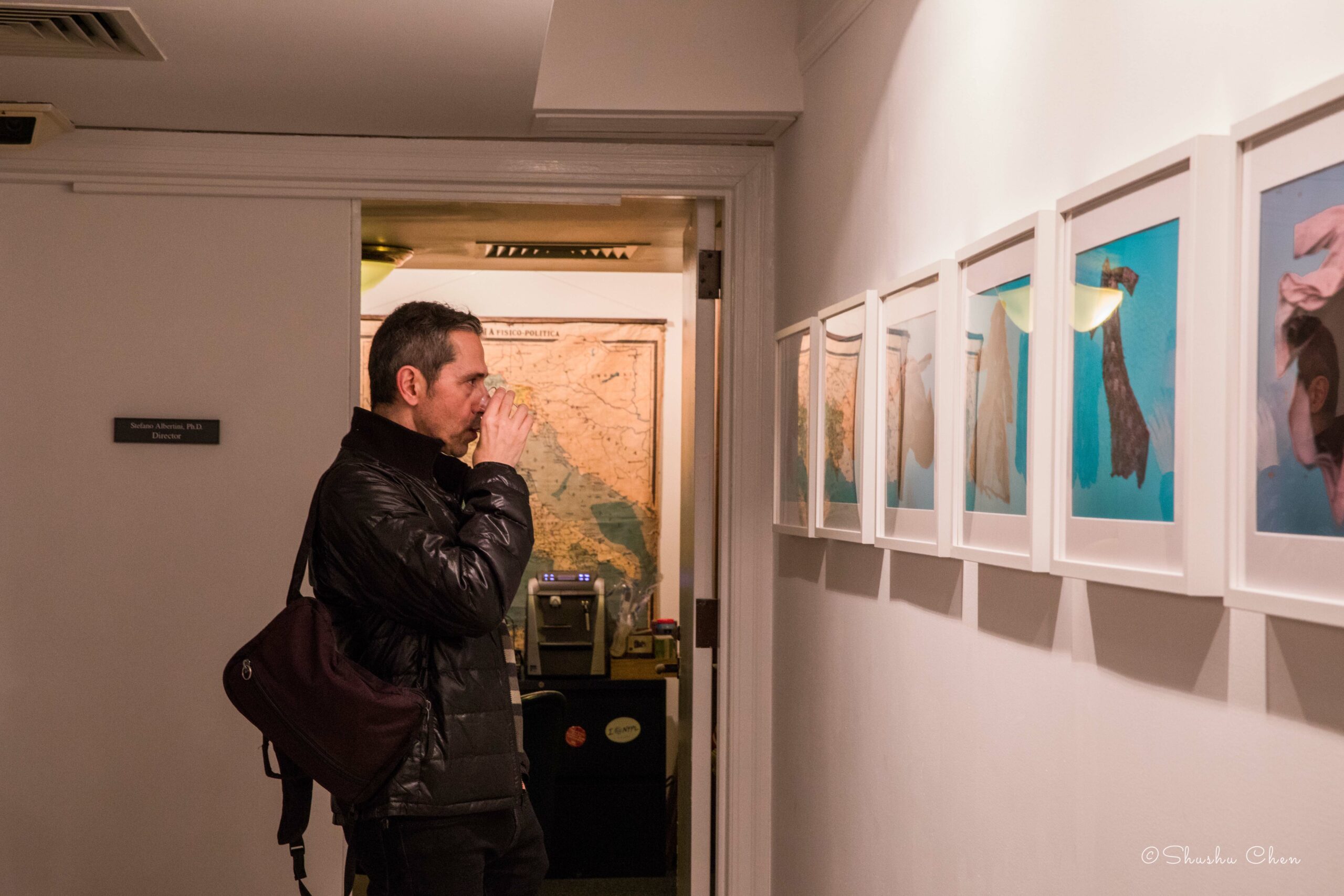 man-drinking-wine-and-seeing-artworks-on-wall-from-exhibition-migration-at-casa-italiana