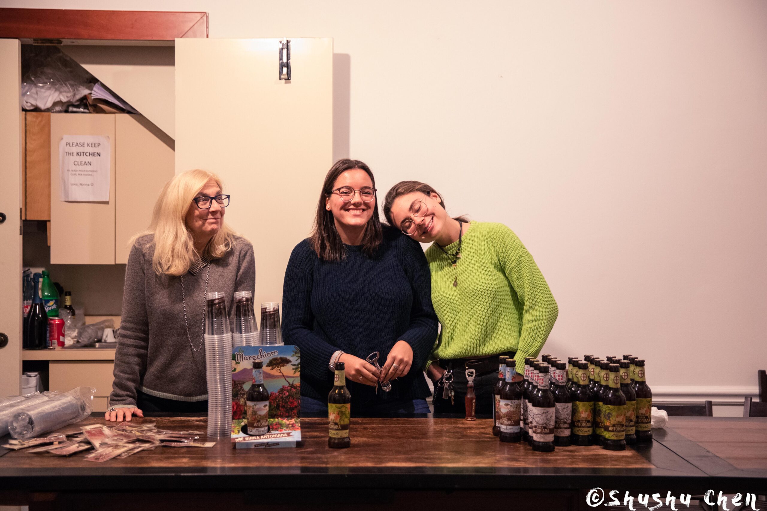 three-smiling-women-standing-behind-a-counter-with-beer-bottles-from-ny-premiere-screening-of-arrangiarsi-and-presentation-at-casa-italiana