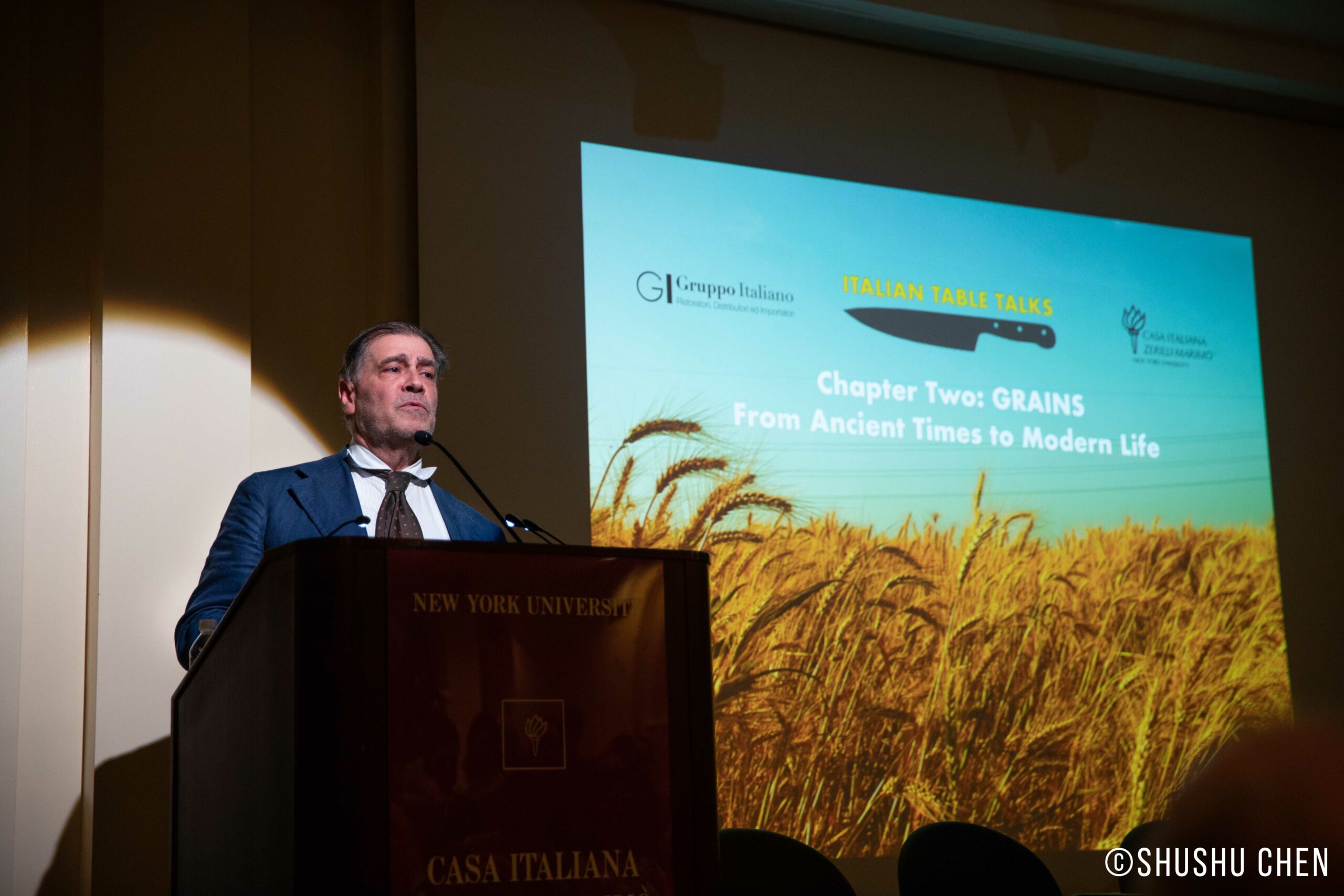 speaker-talking-image-being-displayed-on-projector-screen-from-italian-table-talks-grains-at-casa-italiana