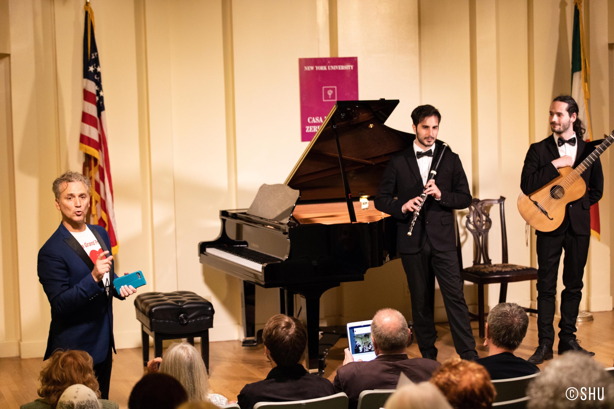 man-talking-and-musicians-holding-guitar-and-flute-from-concert-ibla-foundation-winners-at-casa-italiana