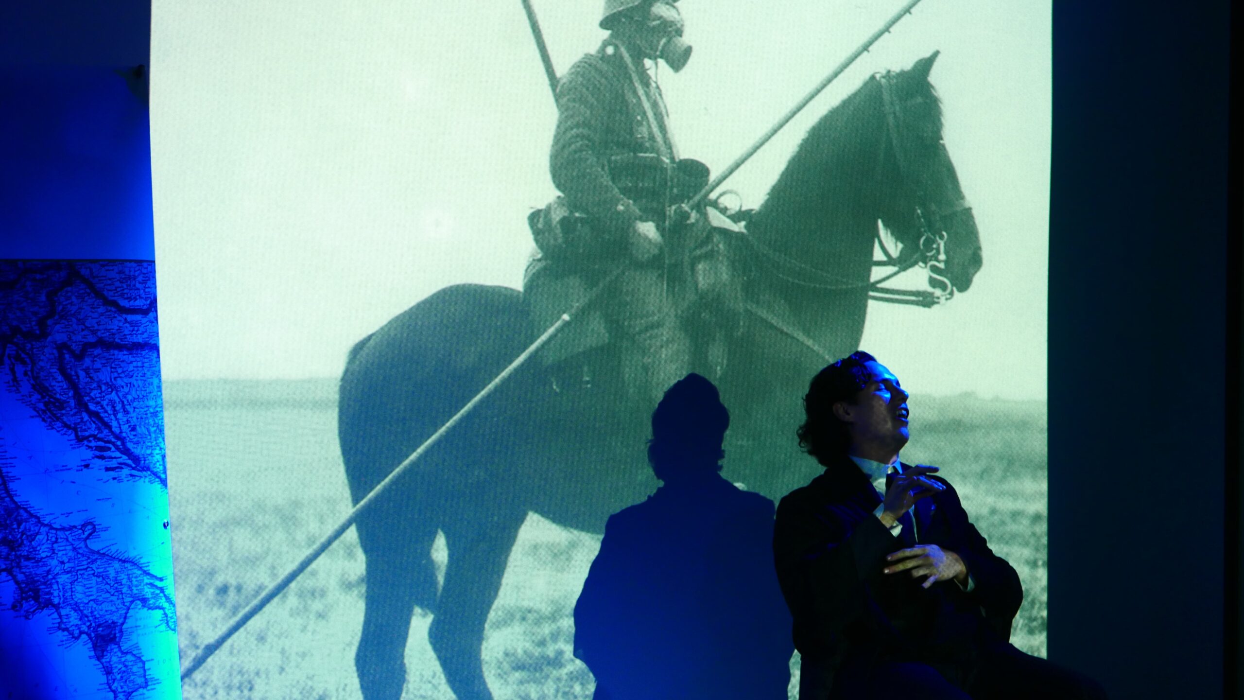 artist-performing-and-image-being-displayed-on-projector-screen-from-treni-ed-eroi-at-casa-italiana